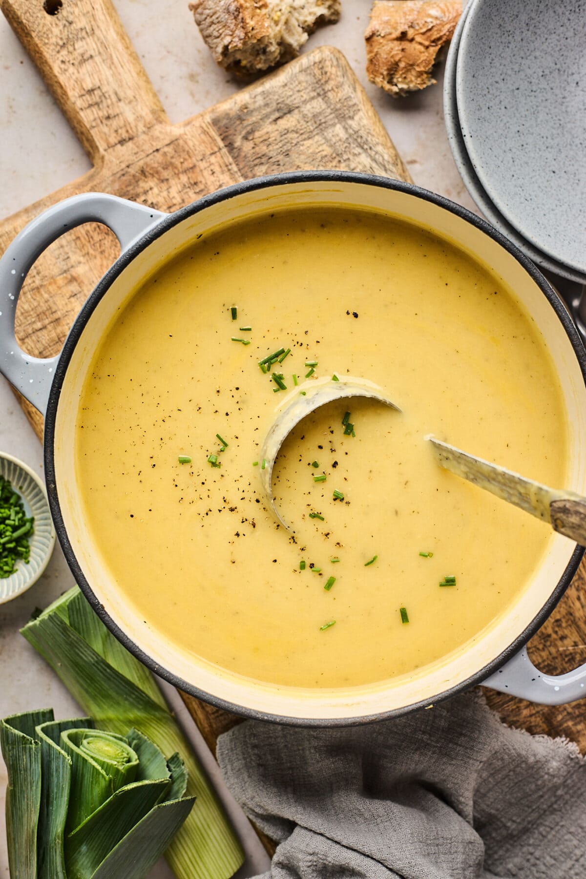 potato leek soup in large pot with herbs and ladle.