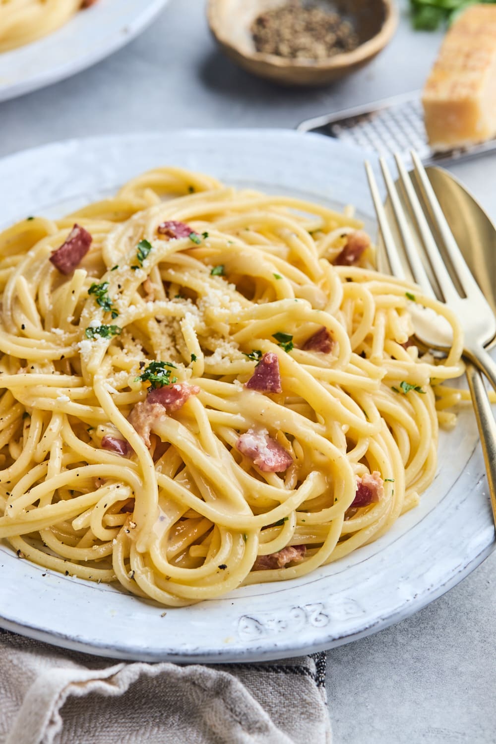spaghetti carbonara with bacon on plate with fork and spoon.