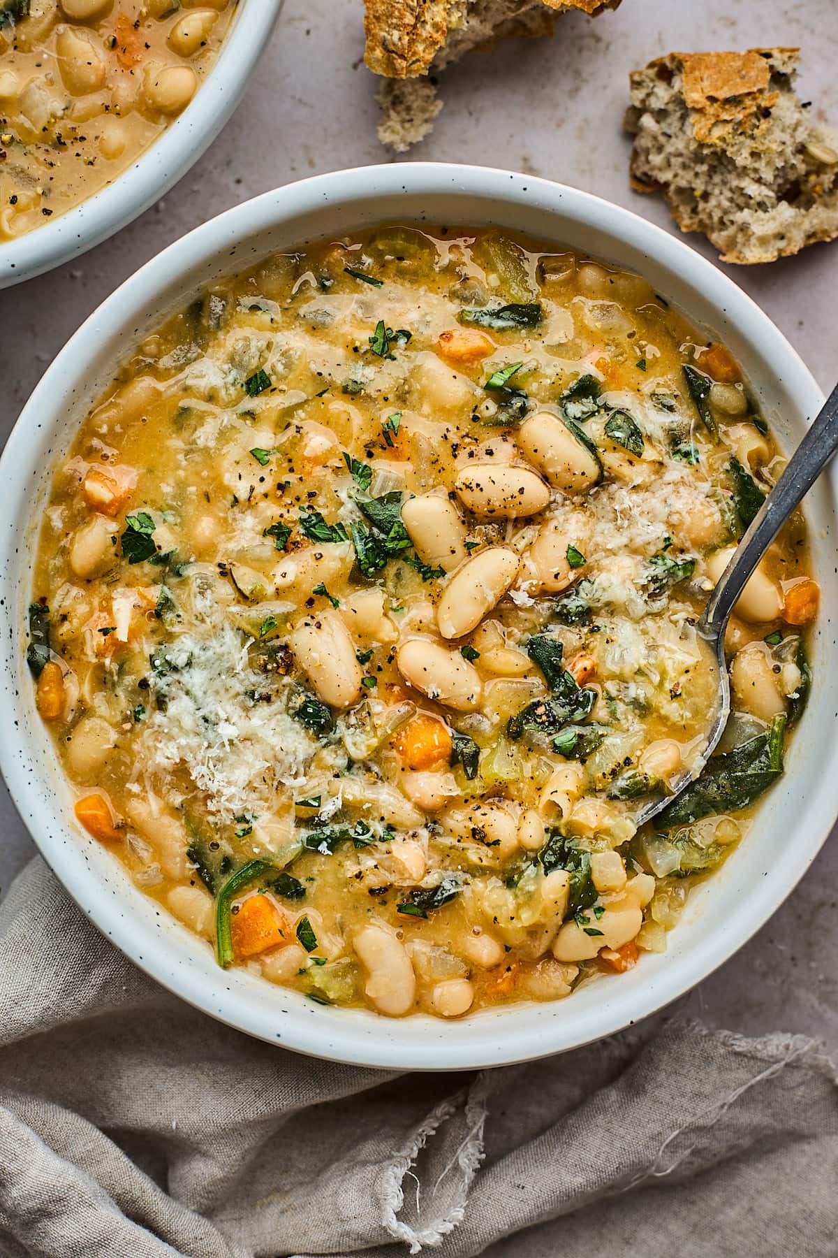 white bean soup with Parmesan cheese in bowl with spoon.