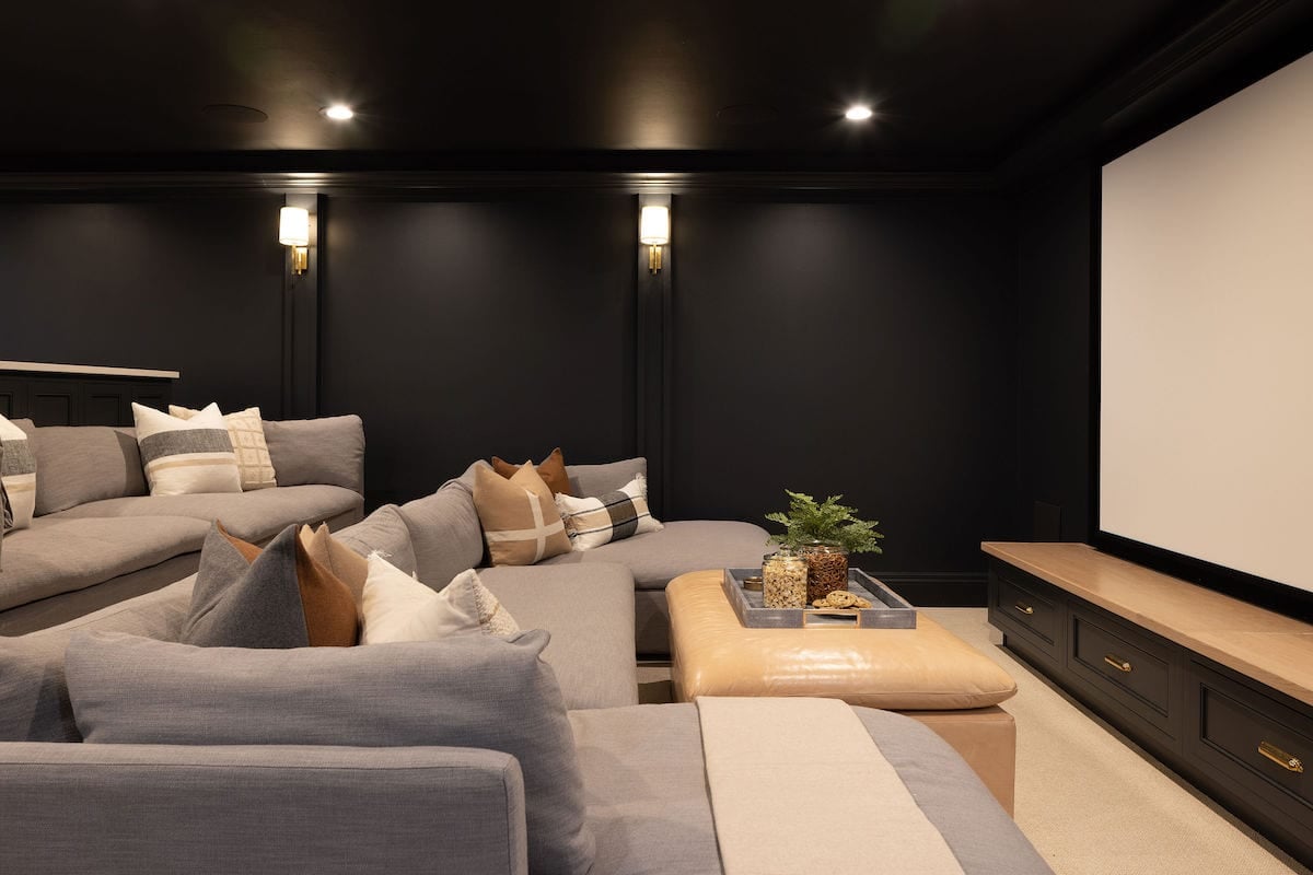 basement theatre room with black walls and sconces.