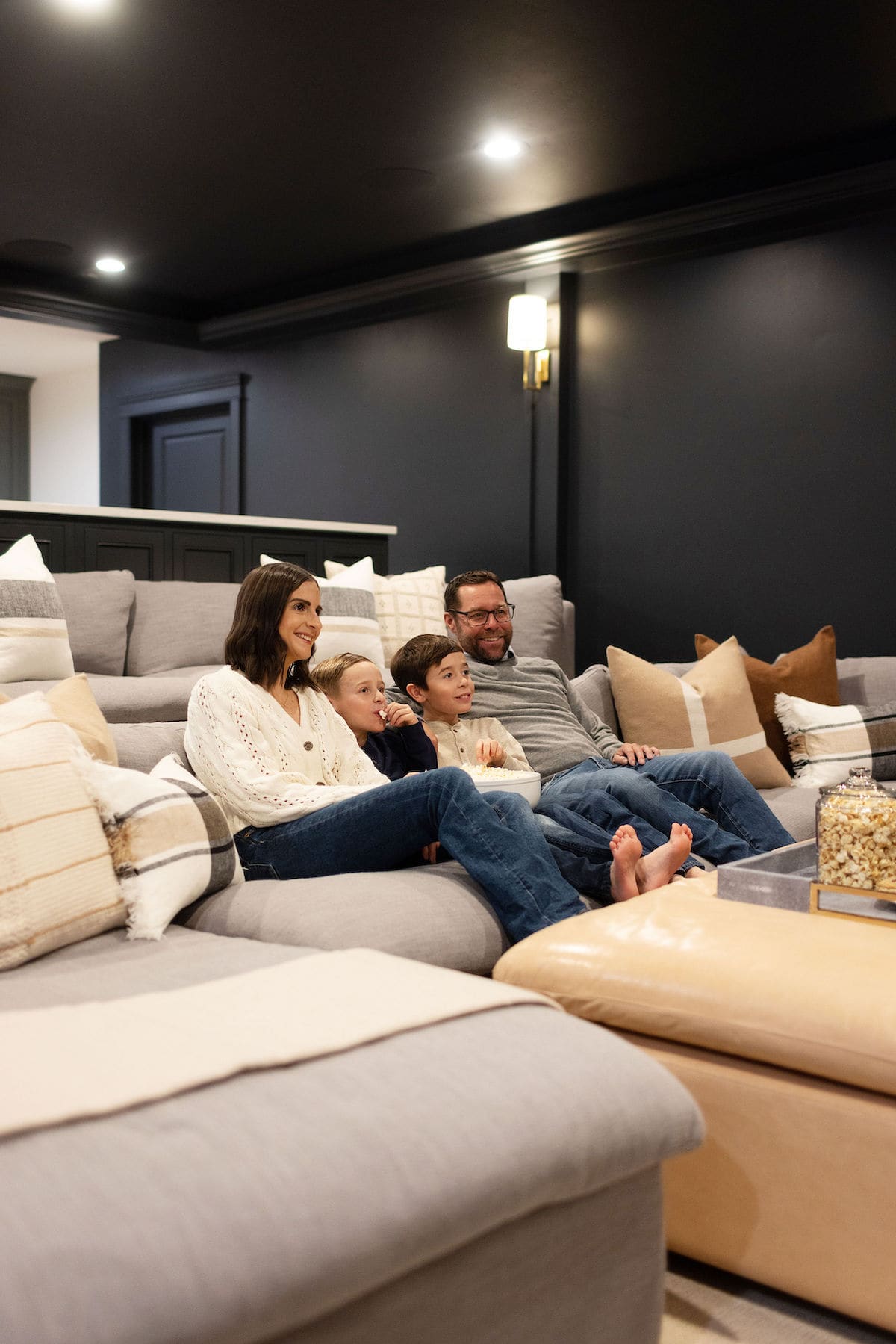 family watching movie in basement theatre room with popcorn.