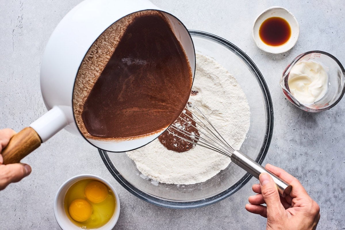 chocolate butter mixture being added to dry ingredients to make chocolate cake.