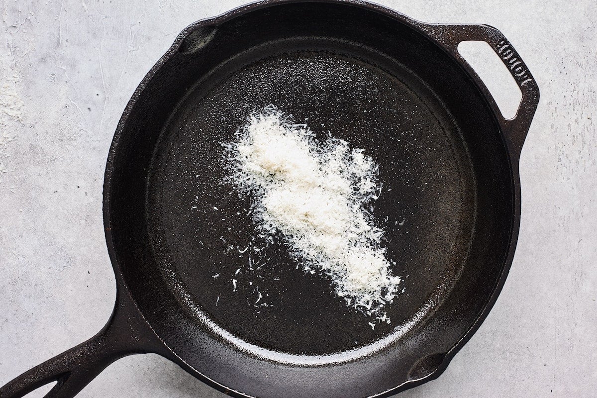 grated parmesan cheese sprinkled in hot cast iron skillet to make grilled cheese.