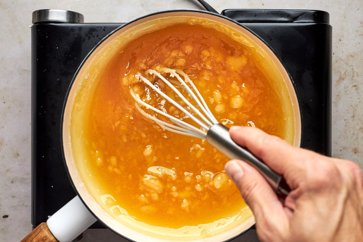 whisking salted caramel sauce in pan on stove.