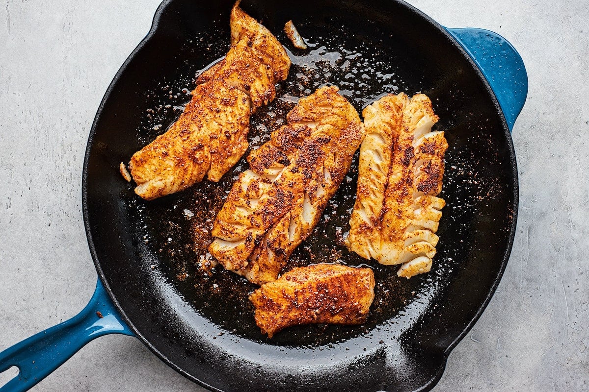 cod in cast iron skillet with seasoning for fish tacos.