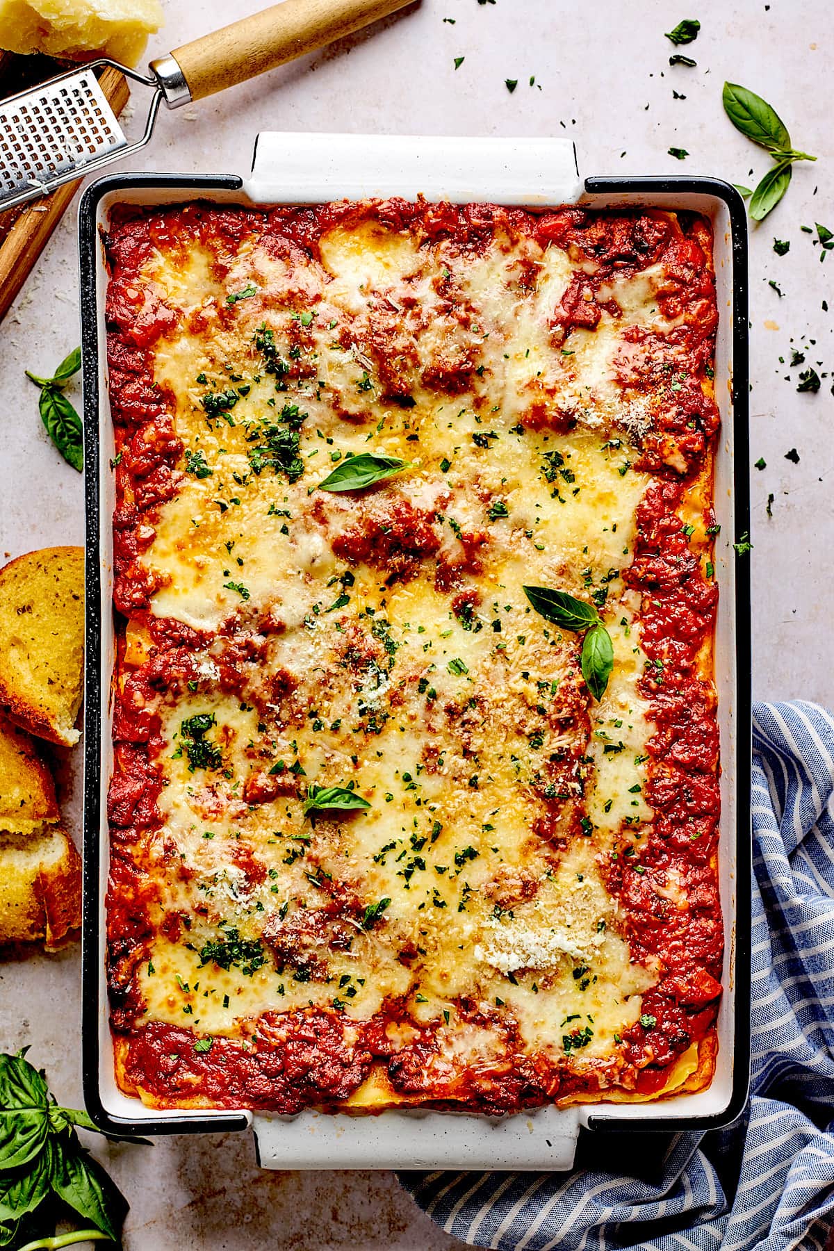 homemade lasagna in pan with fresh basil and parmesan cheese.
