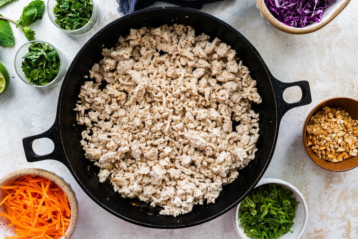 ground chicken being cooked in cast iron skillet.