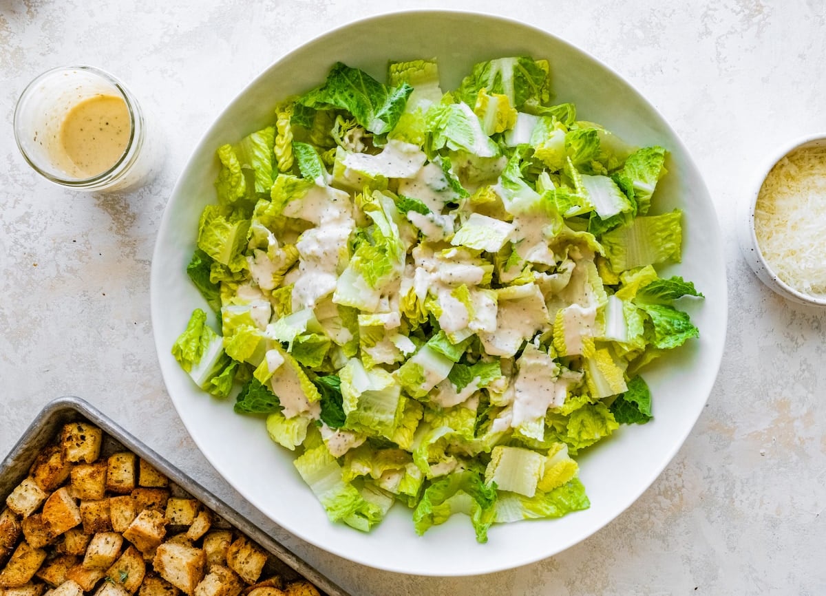 romaine lettuce in bowl tossed with Caesar dressing.