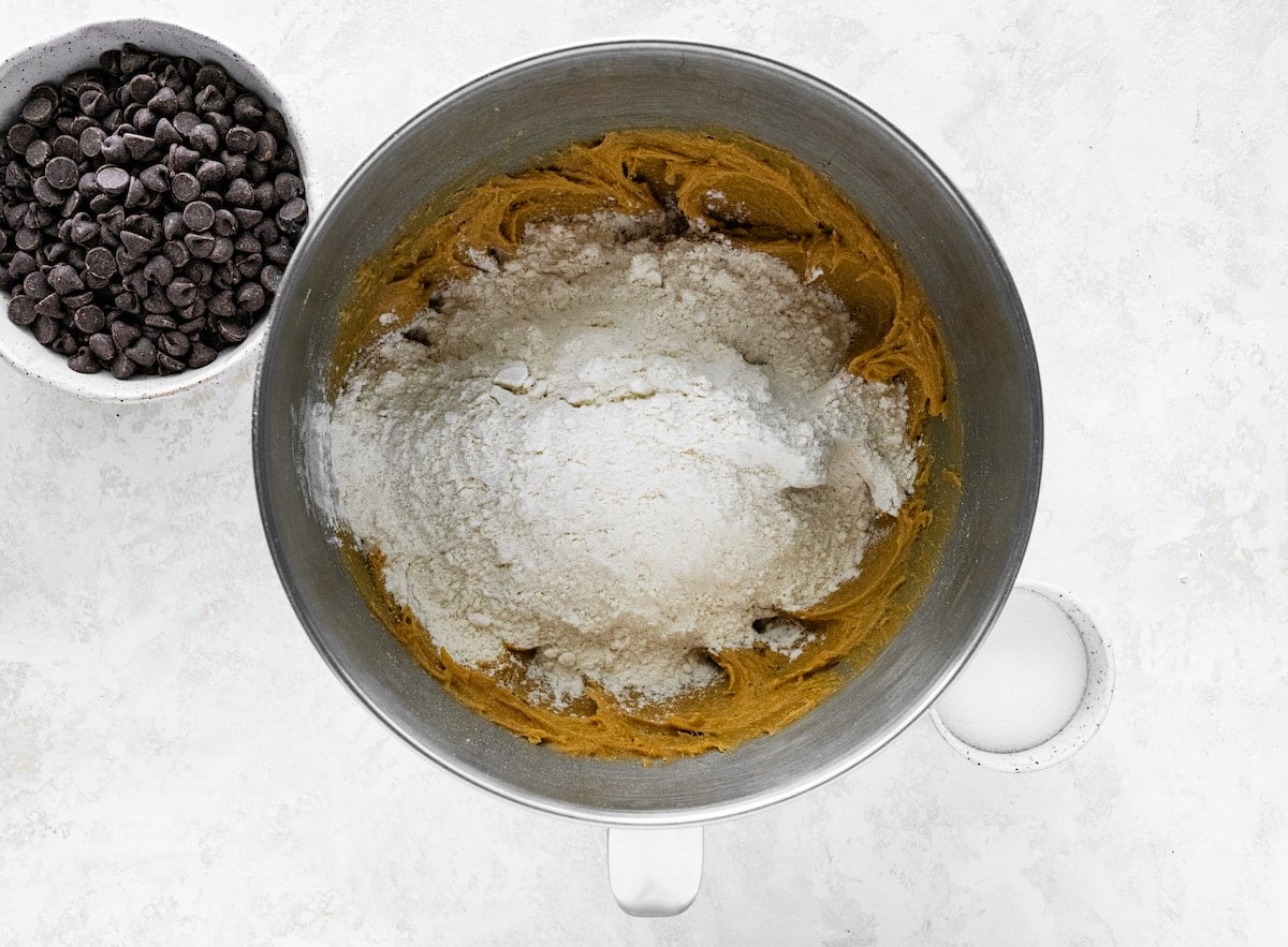 dry ingredients being added to peanut butter cookie dough in mixing bowl.