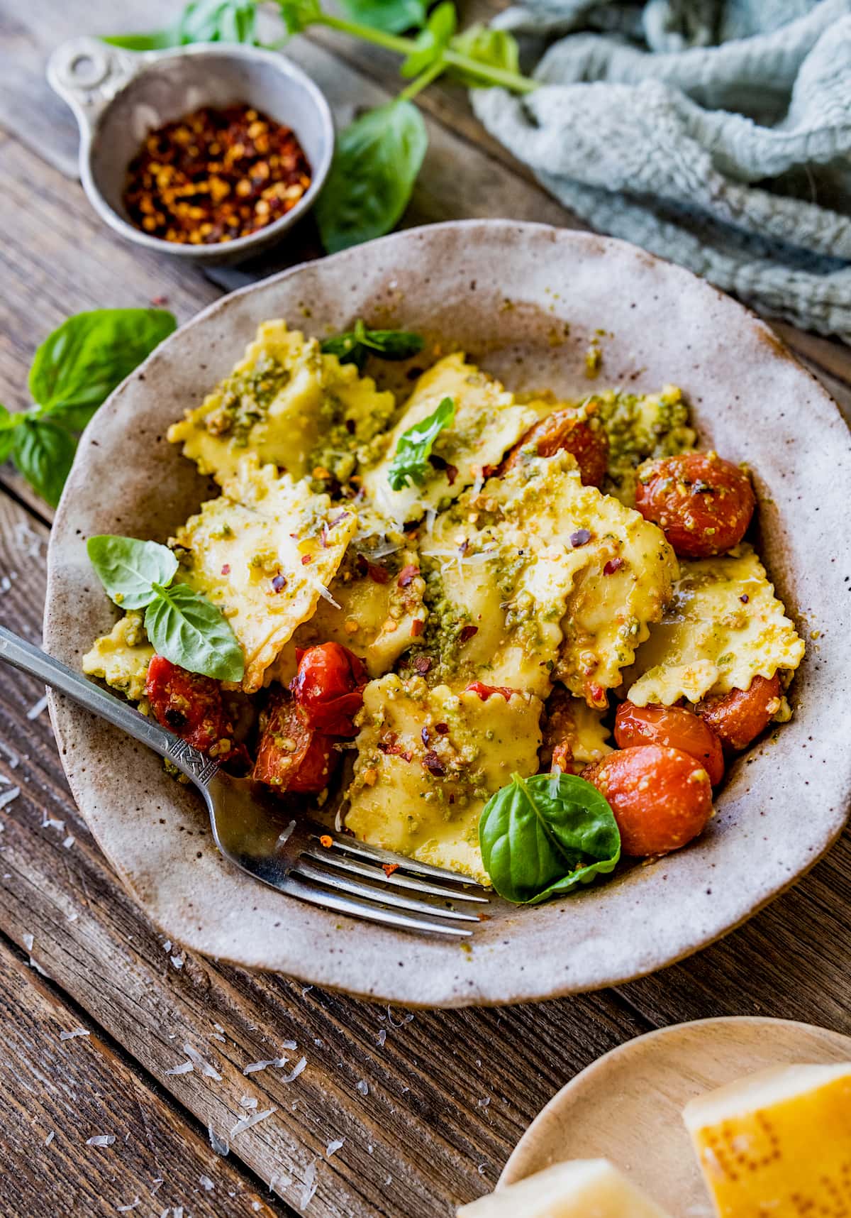 pesto ravioli in bowl with tomatoes and fork.