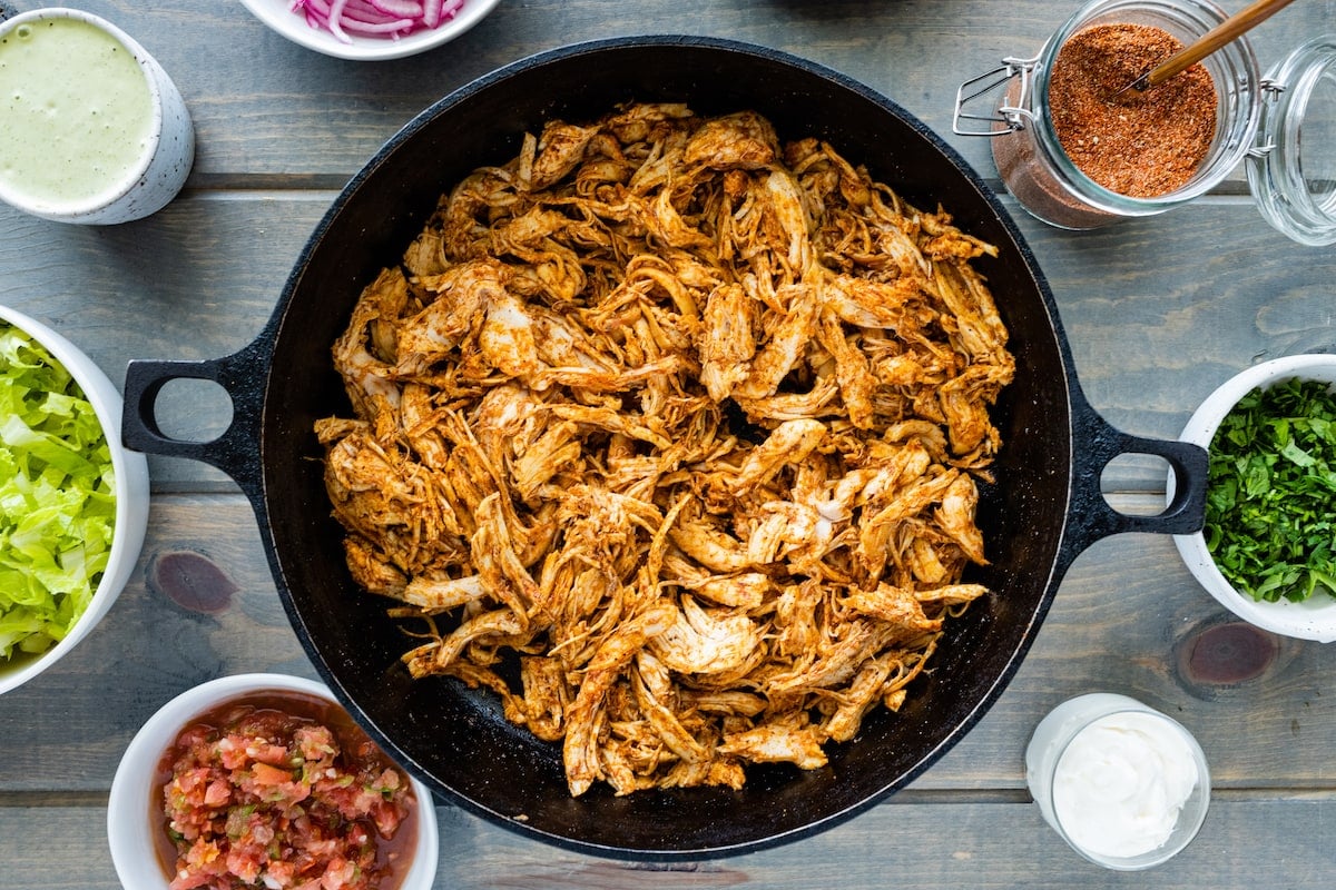 shredded chicken in cast iron skillet with taco seasoning.