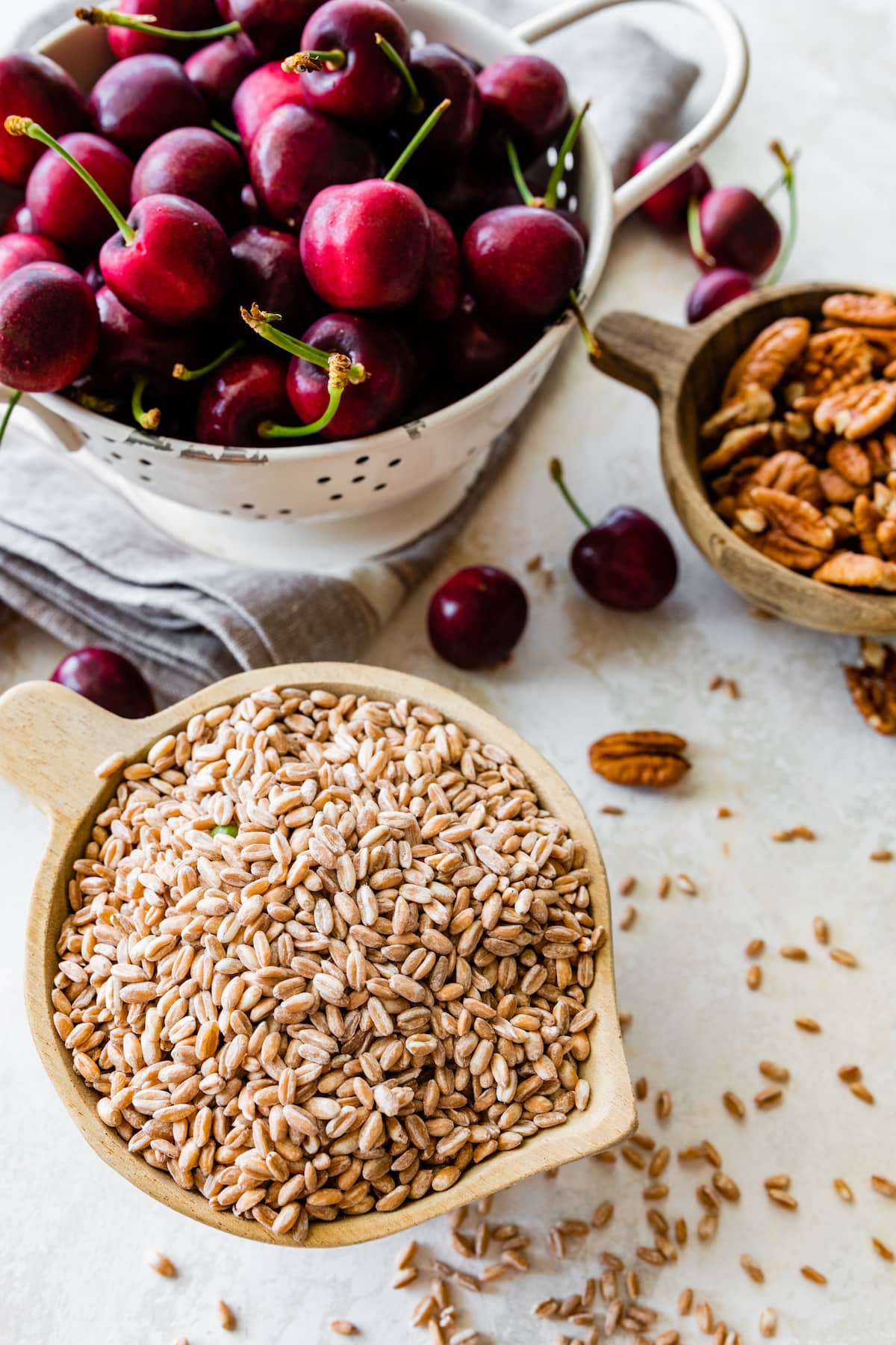 fresh cherries in strainer with farro and pecans in bowl.