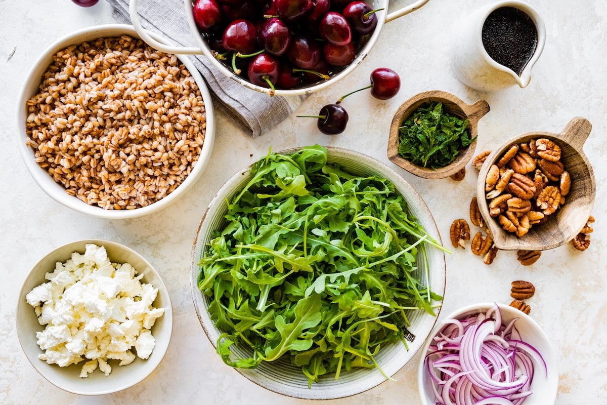 ingredients to make cherry arugula farro salad in bowls.