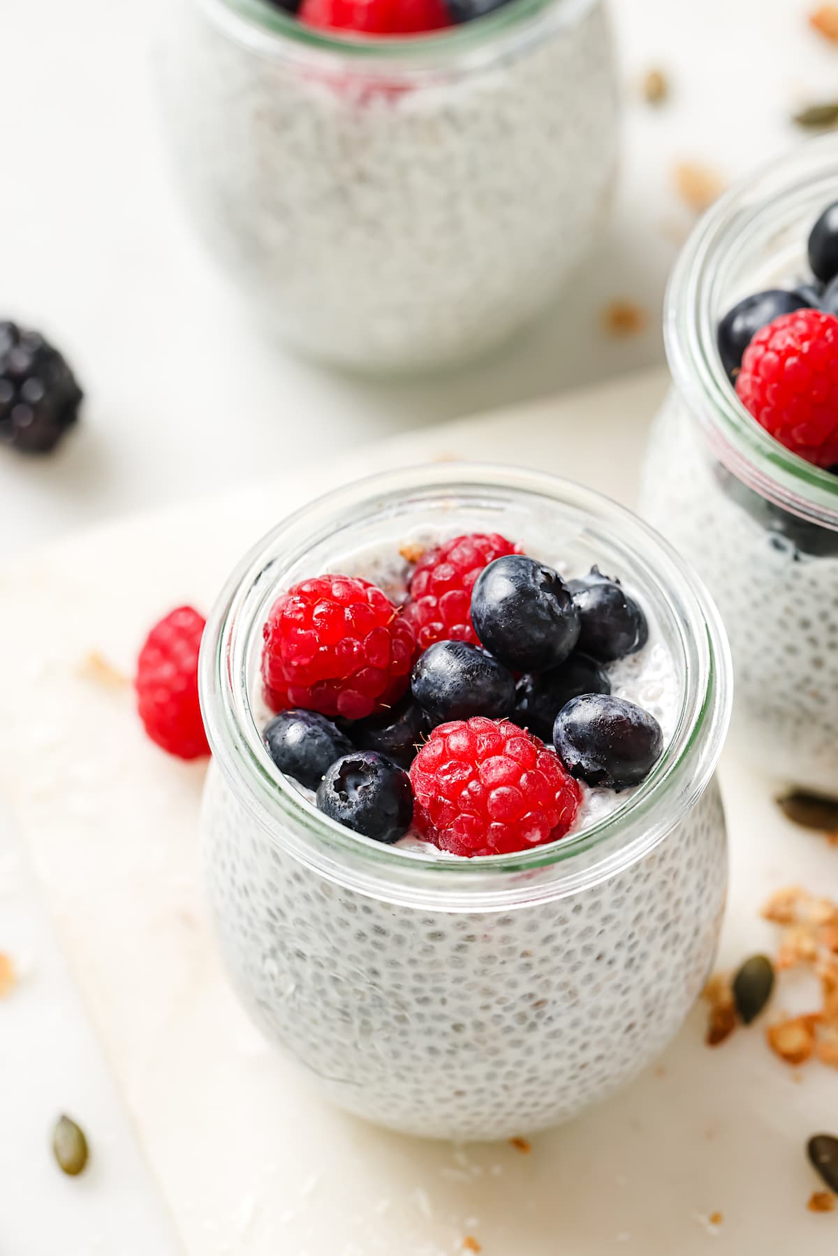 chia pudding in small glass jar with berries on top.