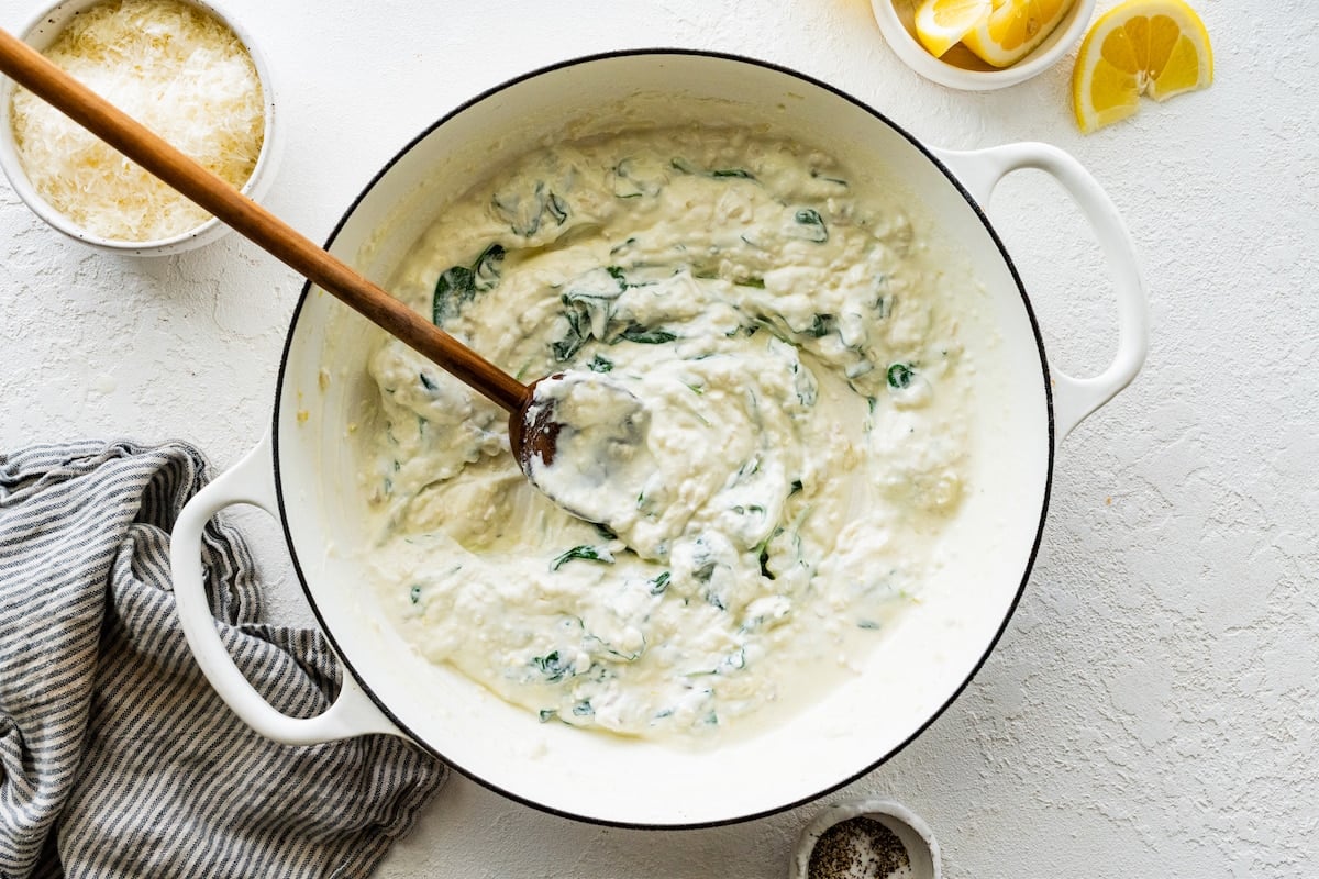 lemon ricotta pasta sauce in white pot with wooden spoon.