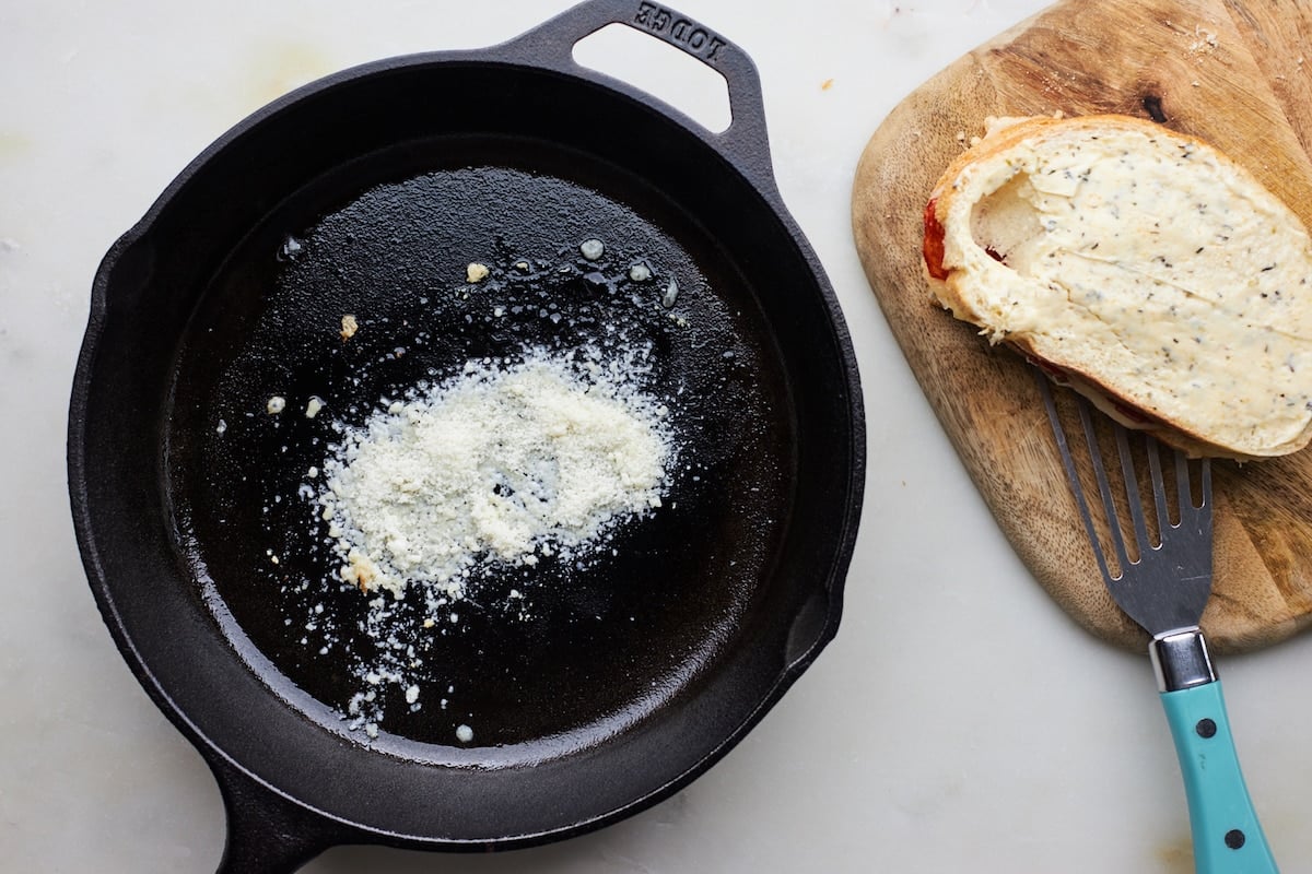 Parmesan cheese in cast iron skillet to make cheese crust on pizza grilled cheese.