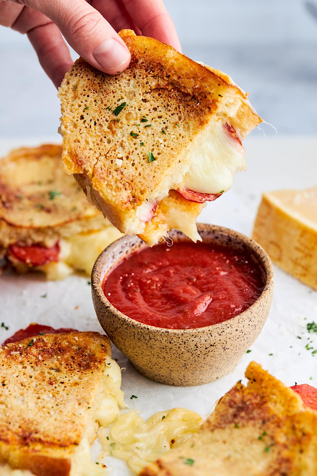 pizza grilled cheese being dipped into a bowl of pizza sauce.