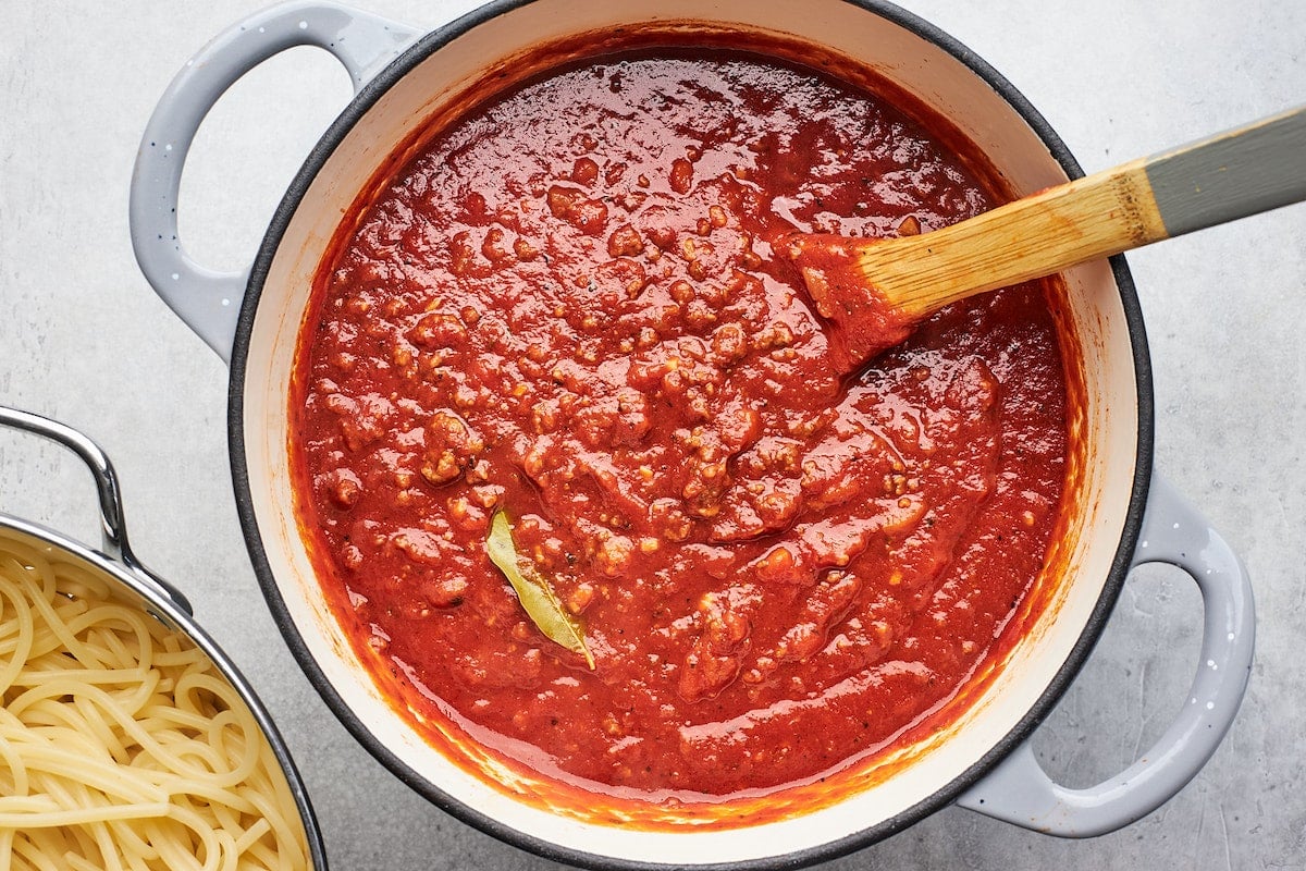 spaghetti sauce simmering in large pot with wooden spoon.