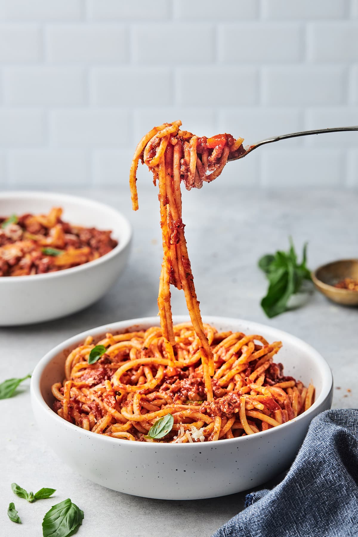 spaghetti with meat sauce being twirled on fork in pasta bowl.