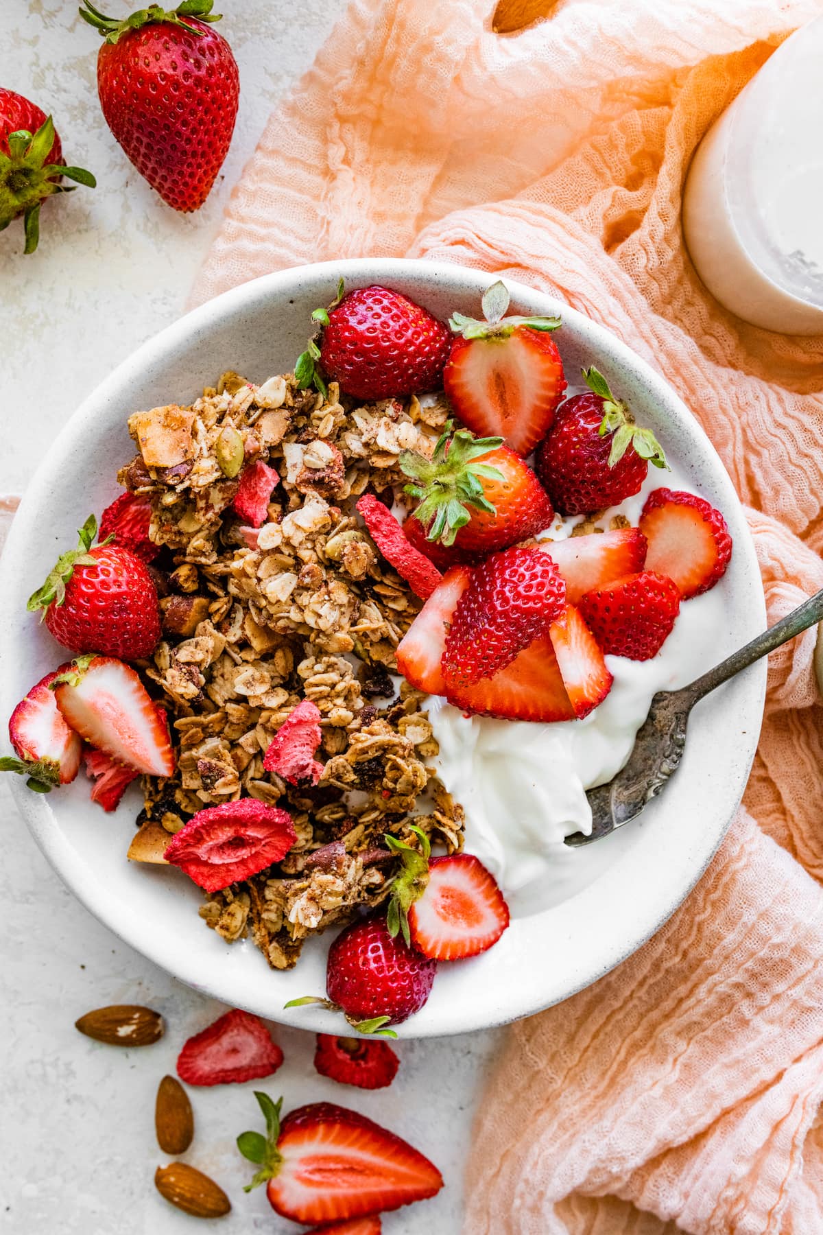 bowl of Greek yogurt with strawberry granola and fresh strawberries.