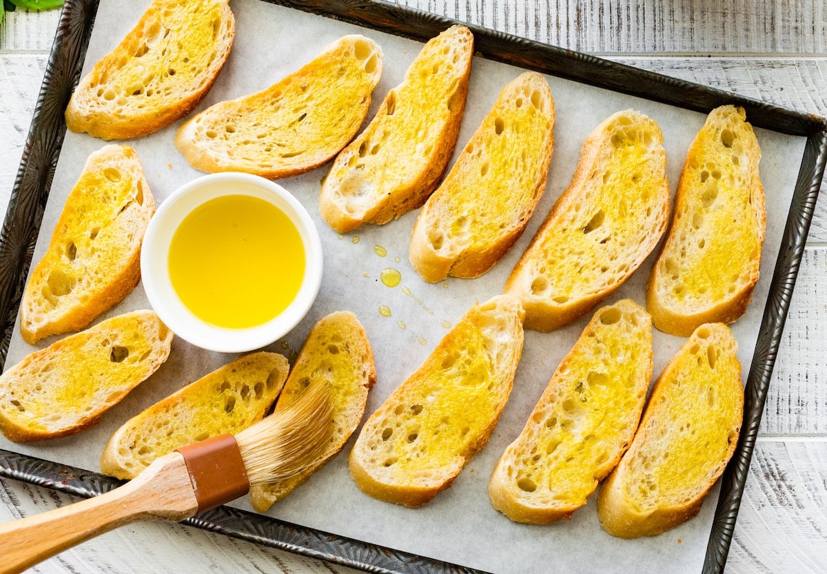 baguette slices on baking sheet with parchment paper brushed with olive oil.