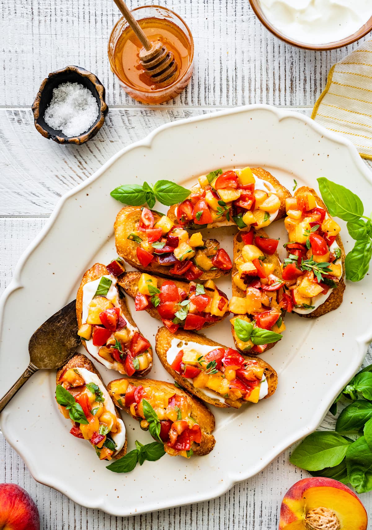 peach tomato bruschetta with whipped cottage cheese and basil on serving platter.