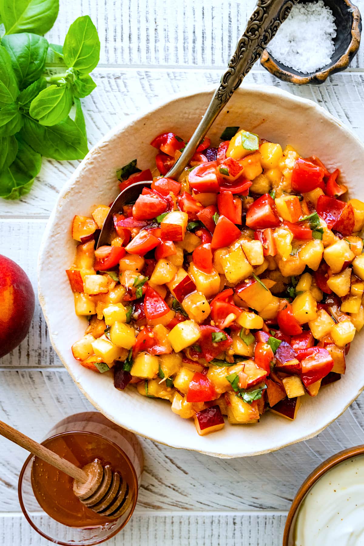 chopped peaches, tomatoes, basil, garlic, and olive oil in bowl to make peach tomato bruschetta.