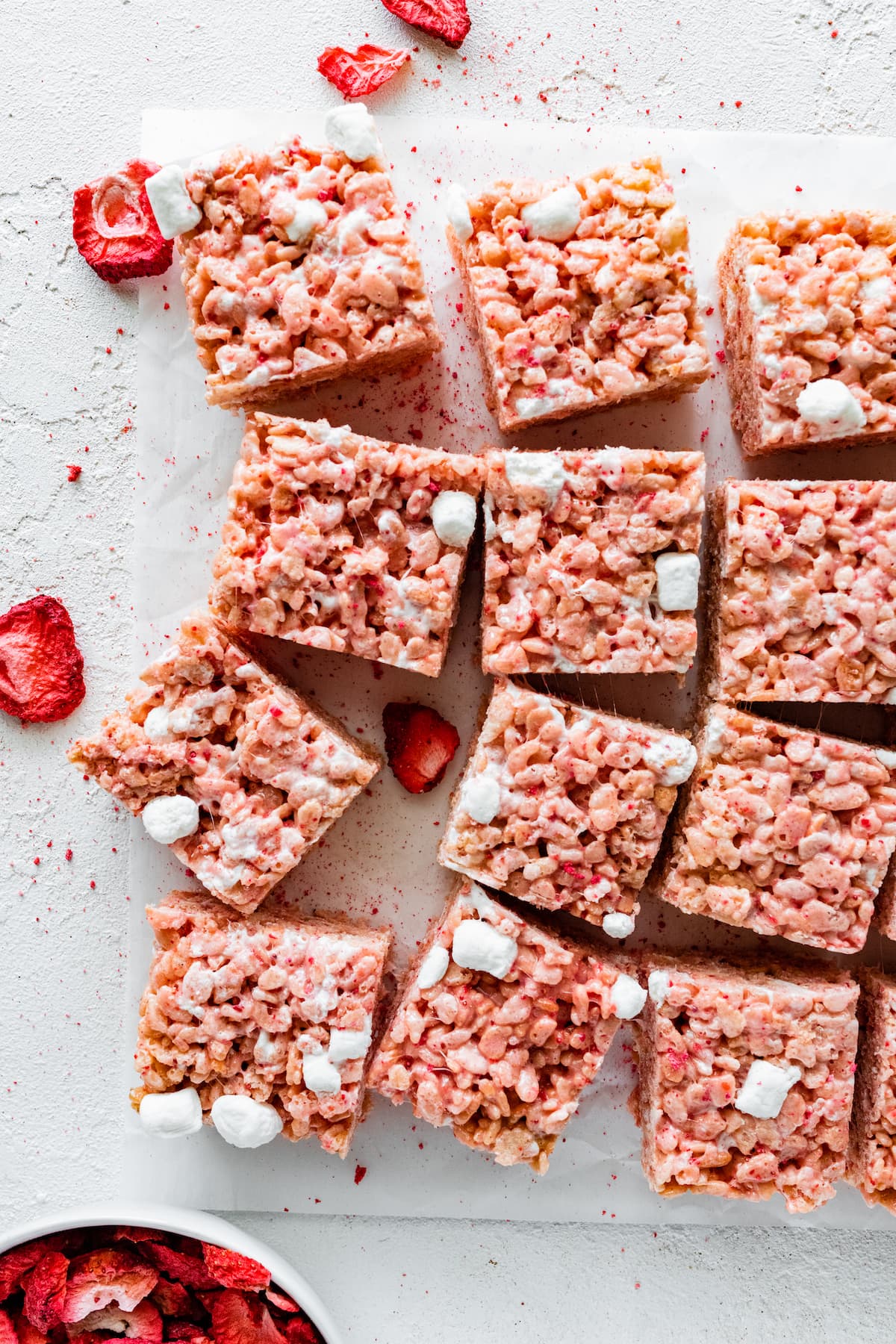 strawberry rice krispie treats cut into squares on parchment paper.