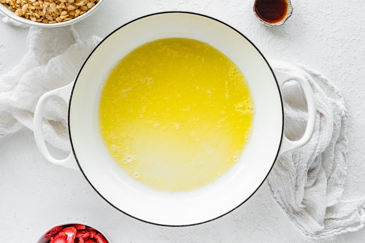 melted butter in large white pot to make strawberry rice krispie treats.