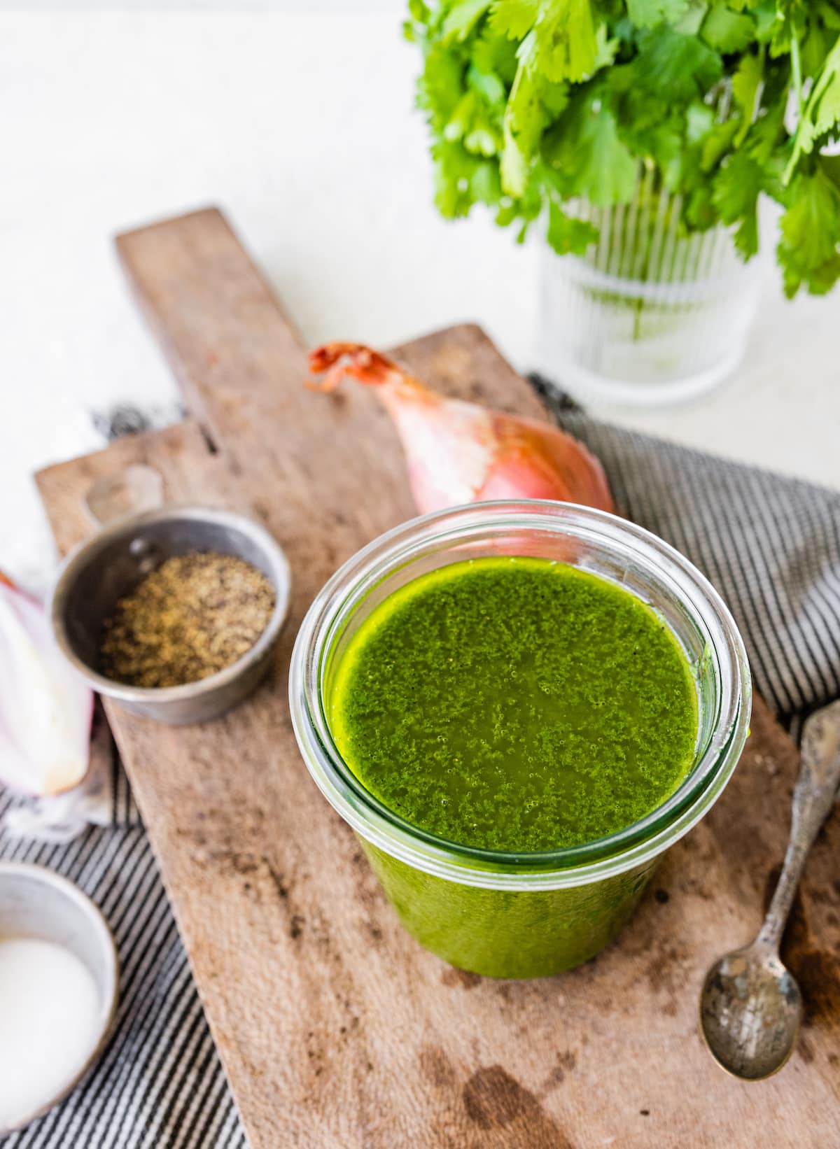 cilantro lime vinaigrette in glass jar on wood board with spoon on side.