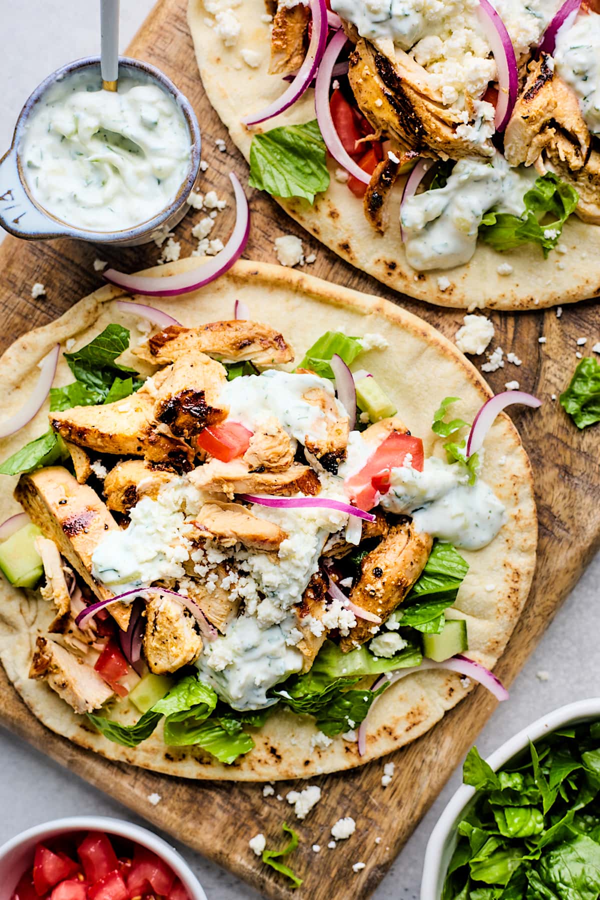 chicken gyros in pita bread with tzatziki, tomatoes, cucumbers, lettuce, and red onion.