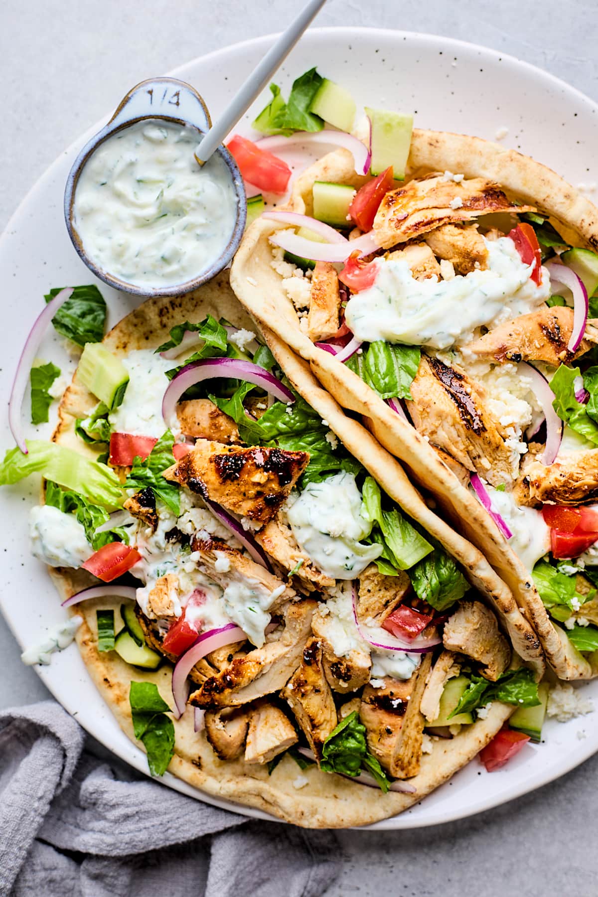 chicken gyros in pita bread with lettuce, tomatoes, cucumber, red onion, and tzatziki sauce.