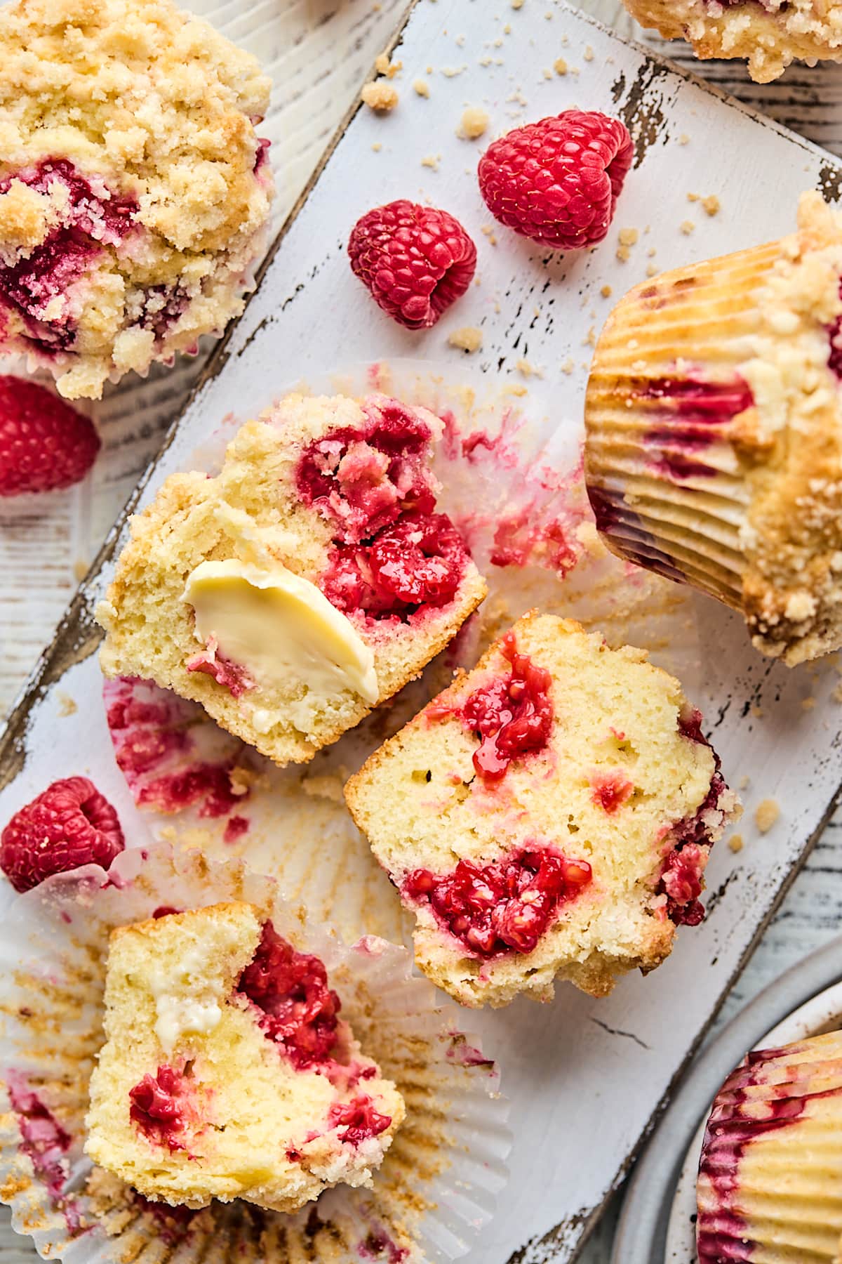 raspberry muffin cut in half with fresh raspberries and butter.