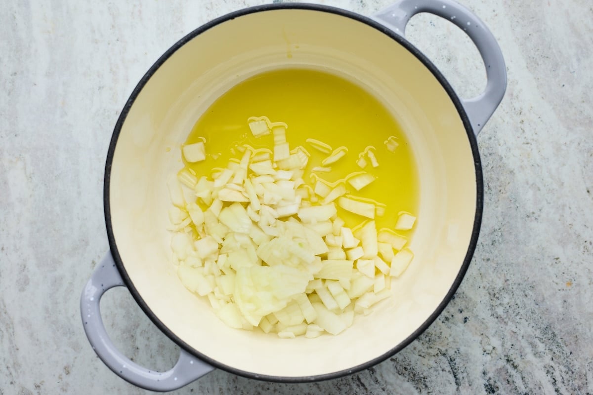 onions being sautéed in olive oil in a large pot.