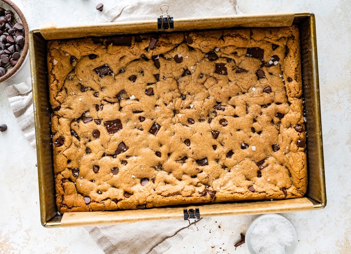 baked brown butter chocolate chip cookie bars in pan with flaky seas salt.