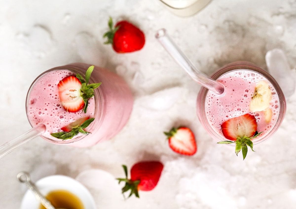 strawberry banana smoothies in glasses with straws.
