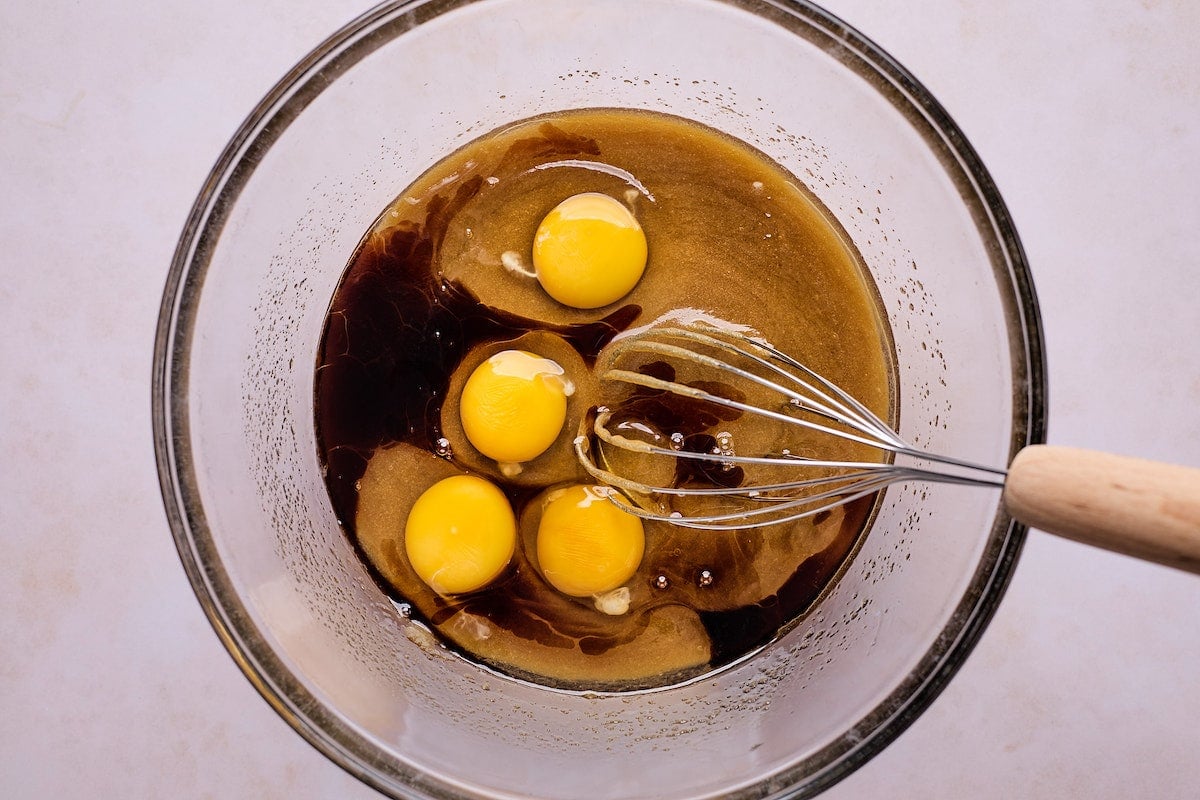 eggs being whisked with sugars in mixing bowl to make raspberry brownies.