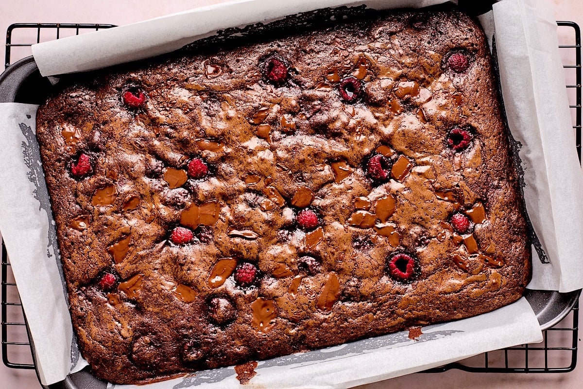 baked raspberry brownies in pan with parchment paper.