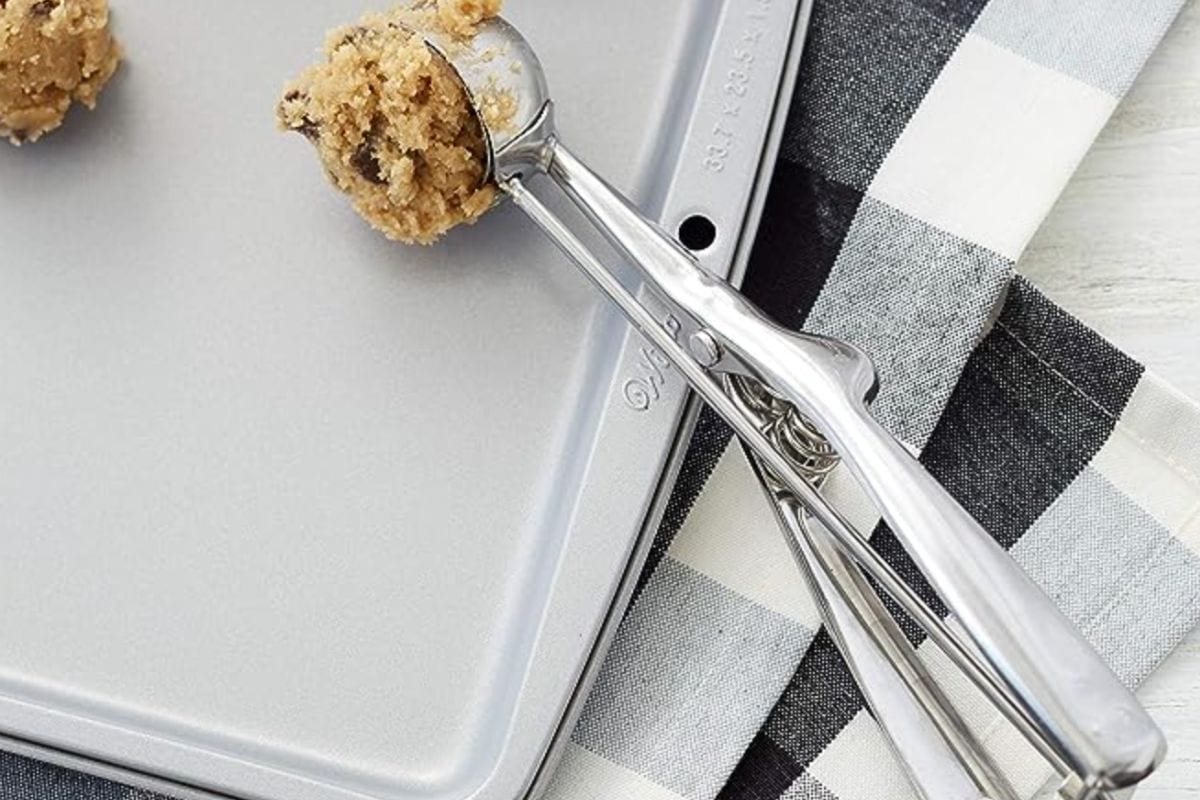cookie scoop scooping cookie dough onto baking sheet.