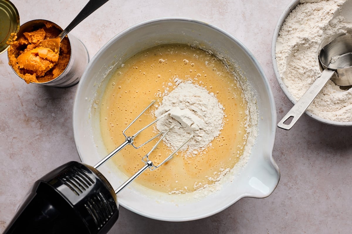 pumpkin bundt cake batter being mixed with hand mixer in bowl.