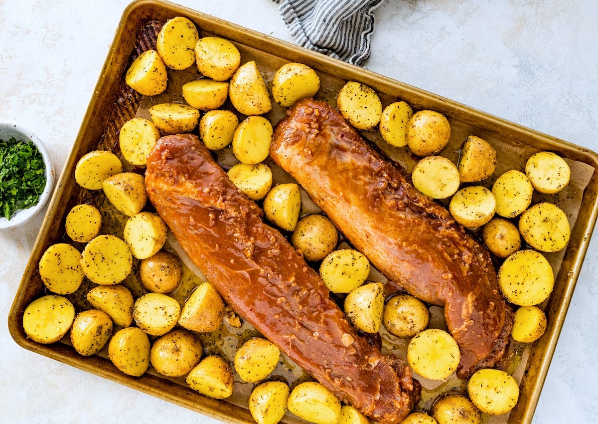 pork tenderloins on sheet pan with seasoned potatoes.