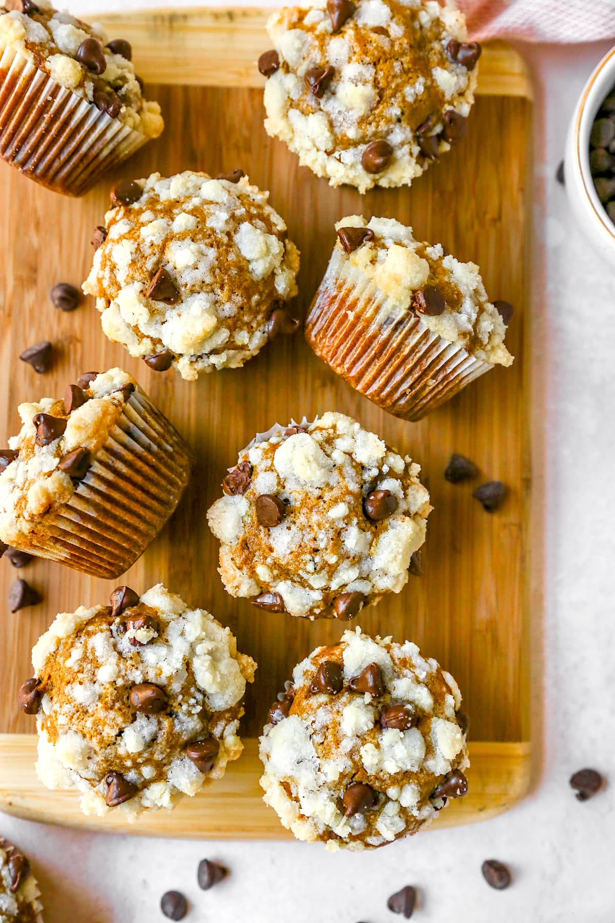 pumpkin chocolate chip. muffins on wood cutting board.