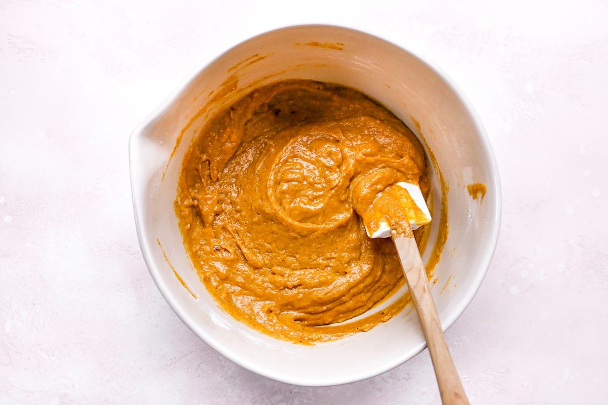 pumpkin chocolate chip muffin batter in mixing bowl with spatula.