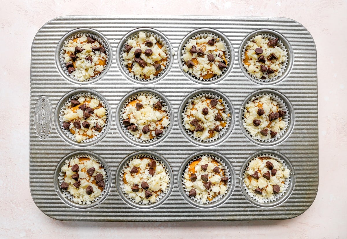 pumpkin chocolate chip muffin batter with streusel topping in muffin pan.