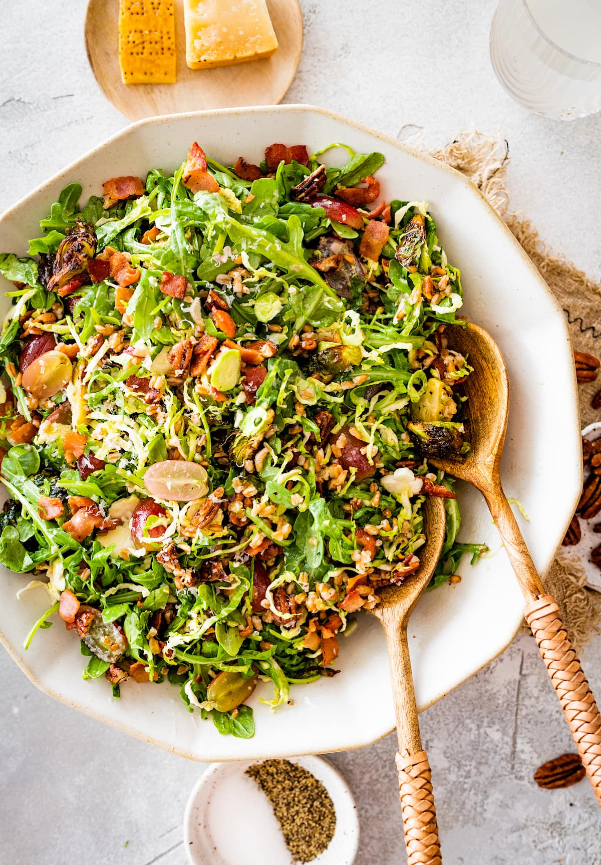 bacon brussels sprouts salad in white salad bowl with wood spoons.