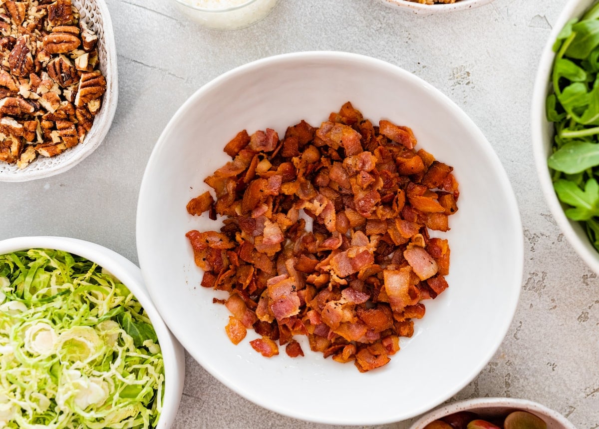 cooked chopped bacon in white bowl to make bacon brussels sprouts salad.
