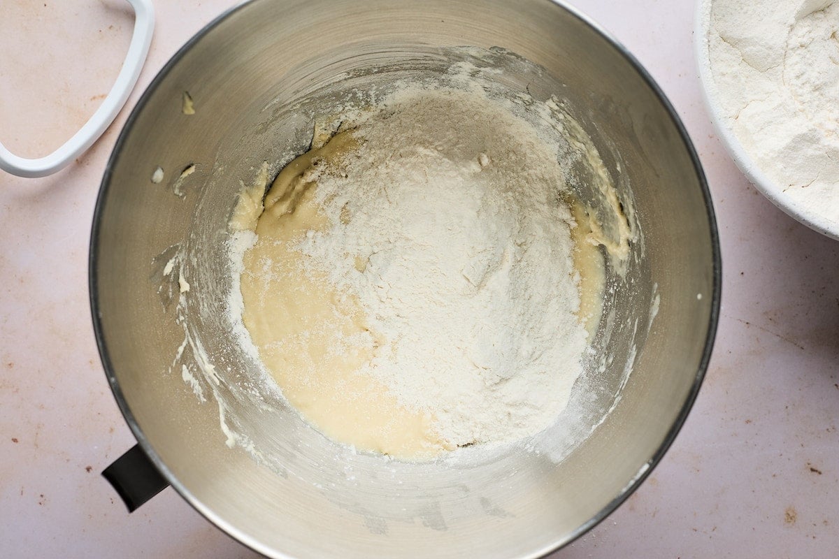 adding flour to dinner roll dough in mixing bowl.