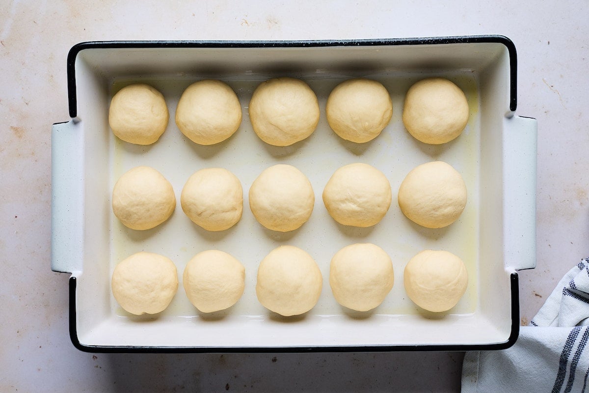 dinner roll dough rolled into balls and placed in baking pan to rise.