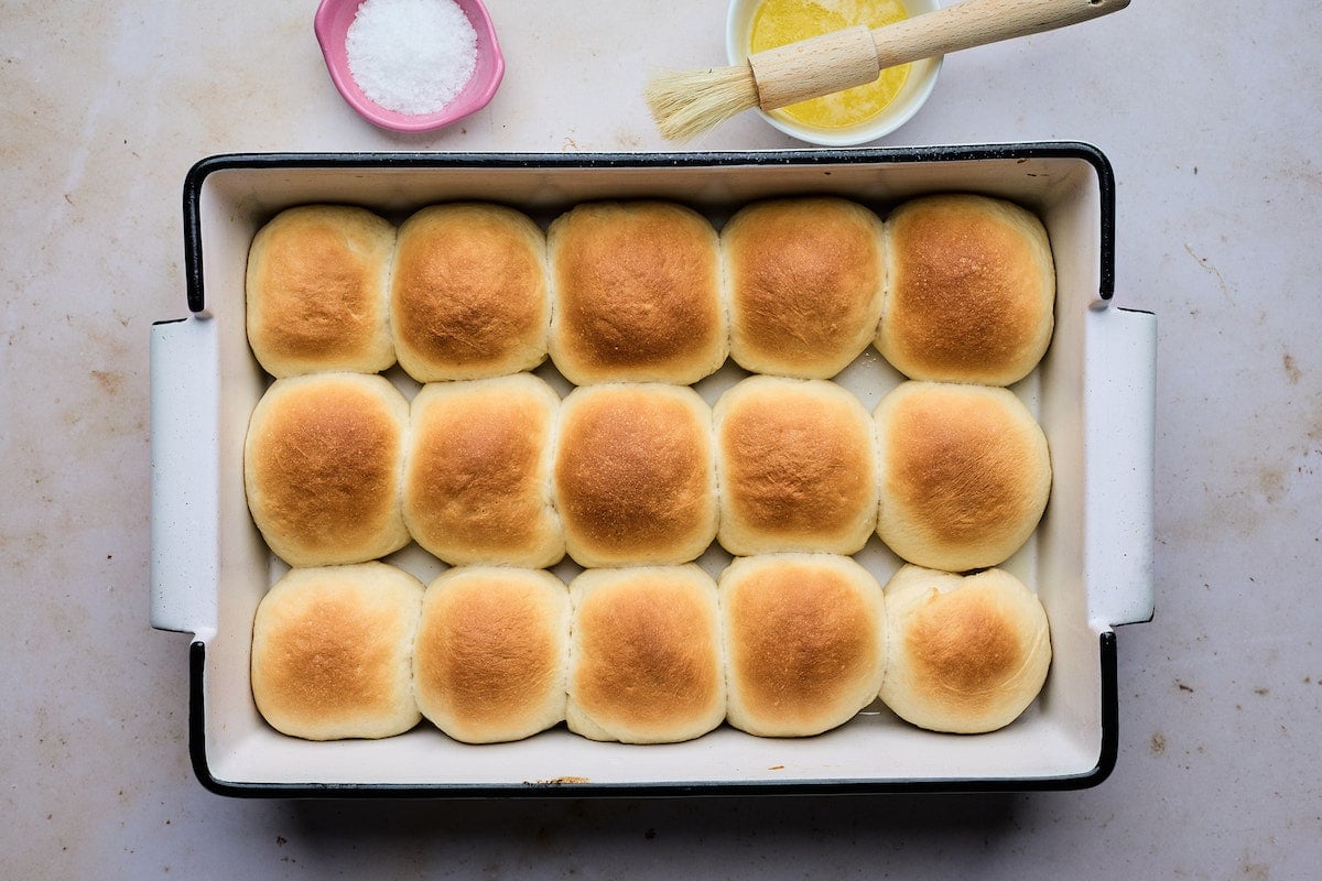 dinner rolls in baking pan getting ready to be brushed with melted butter.