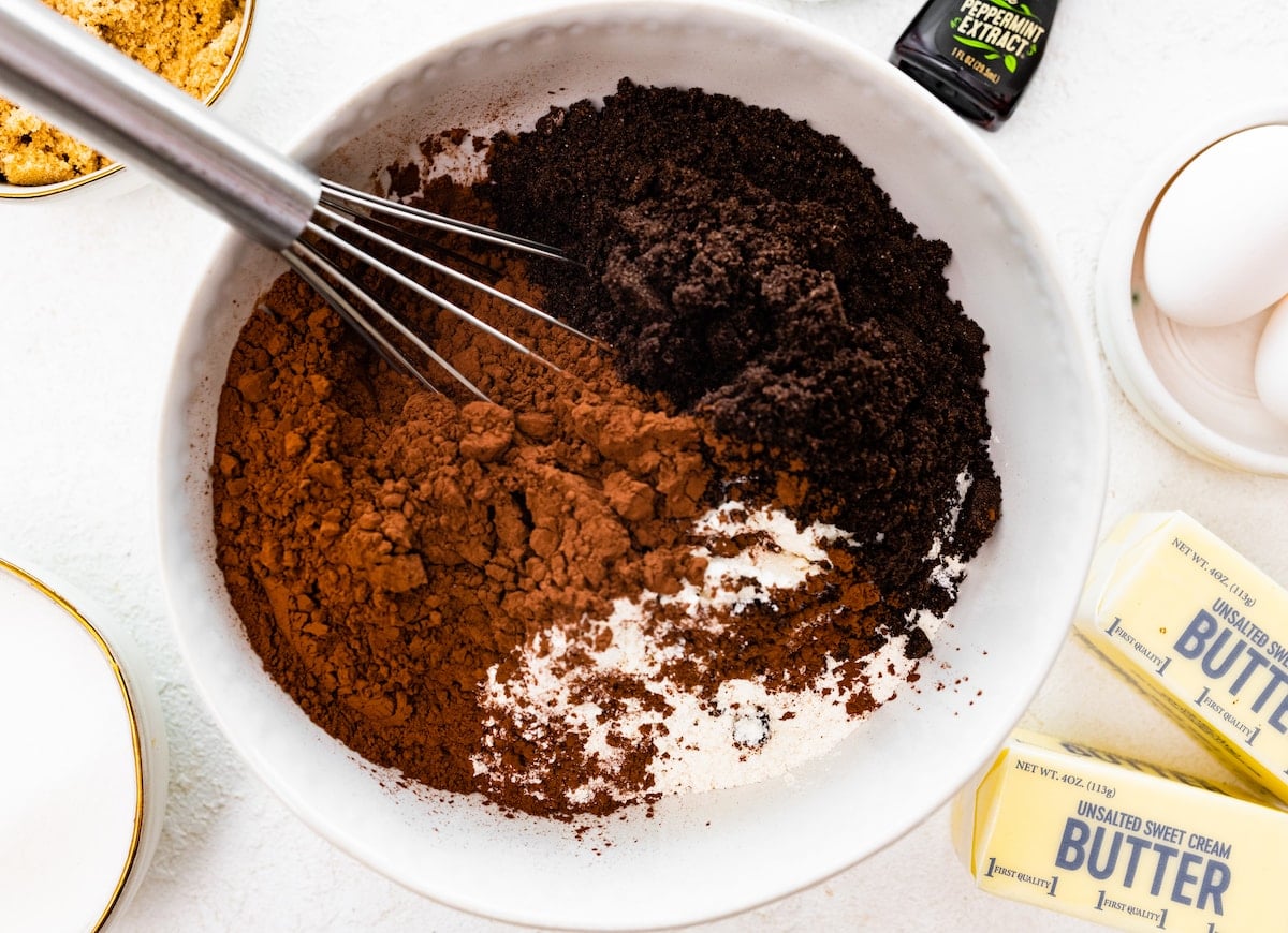 cocoa powder, crushed Oreo cookies, and flour being whisked together in mixing bowl.